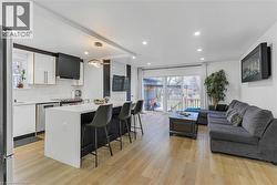 Kitchen featuring open floor plan, white cabinetry, a kitchen breakfast bar, recessed lighting, and hanging light fixtures - 