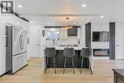 Kitchen with hanging light fixtures, freestanding refrigerator, a breakfast bar area, white cabinetry, and a kitchen island - 