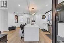 Kitchen featuring a breakfast bar, hanging light fixtures, a kitchen island, white cabinetry, and modern cabinets - 