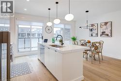 Kitchen featuring dishwasher, modern cabinets, a sink, white cabinetry, and light wood finished floors - 