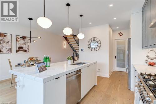 Kitchen with modern cabinets, a sink, light wood-type flooring, appliances with stainless steel finishes, and a kitchen island with sink - 151C Port Robinson Road, Pelham, ON - Indoor Photo Showing Kitchen With Double Sink With Upgraded Kitchen