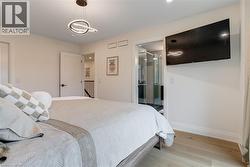 Bedroom with light wood finished floors, baseboards, and a notable chandelier - 