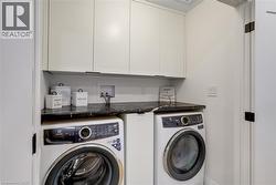 Washroom with washing machine and clothes dryer and cabinet space - 