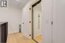 Hall featuring light wood-style flooring, attic access, and baseboards - 