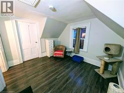 Bonus room with dark vinyl flooring, lofted ceiling, and attic access - 