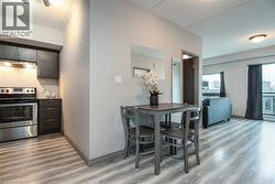 Kitchen featuring stainless steel range with electric cooktop, light wood-style flooring, under cabinet range hood, tasteful backsplash, and dark brown cabinetry - 