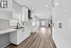 Kitchen featuring white cabinetry, backsplash, light wood-style flooring, modern cabinets, and recessed lighting - 