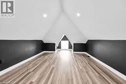 Additional living space featuring light wood-style floors and lofted ceiling - 
