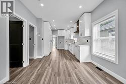 Kitchen featuring white cabinetry, modern cabinets, decorative backsplash, light wood-type flooring, and recessed lighting - 