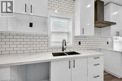 Kitchen featuring white cabinets, wall chimney exhaust hood, and light stone countertops - 