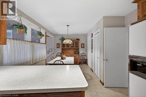 Kitchen with wallpapered walls, light countertops, wood finish cabinetry, a peninsula, and decorative light fixtures - 9 Daleview Court, Hamilton, ON - Indoor