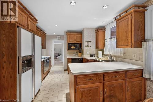 Kitchen with a peninsula, light countertops, black appliances, tasteful backsplash, and wood finish cabinets - 9 Daleview Court, Hamilton, ON - Indoor Photo Showing Kitchen With Double Sink