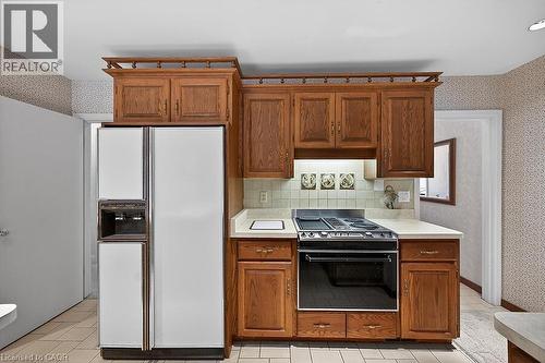 Kitchen featuring wallpapered walls, light countertops, white fridge with ice dispenser, black range with electric stovetop, and wood finish cabinetry - 9 Daleview Court, Hamilton, ON - Indoor Photo Showing Kitchen