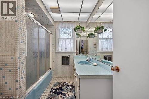 Bathroom featuring vanity, bath / shower combo with glass door, light tile patterned floors, and heating unit - 9 Daleview Court, Hamilton, ON - Indoor Photo Showing Other Room