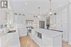 Kitchen featuring a center island, a sink, decorative backsplash, high quality appliances, and white cabinets - 