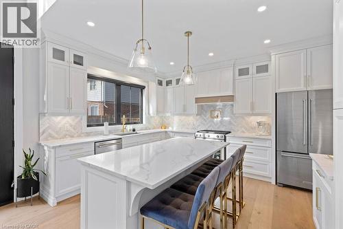 Kitchen with stainless steel appliances, a kitchen island, light wood-style flooring, and white cabinets - 308 Appleby Line, Burlington, ON - Indoor Photo Showing Kitchen With Stainless Steel Kitchen With Upgraded Kitchen