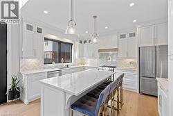 Kitchen with stainless steel appliances, a kitchen island, light wood-style flooring, and white cabinets - 