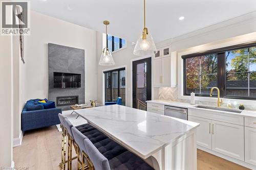 Kitchen with a sink, light stone counters, dishwasher, a wealth of natural light, and a center island - 308 Appleby Line, Burlington, ON - Indoor With Fireplace