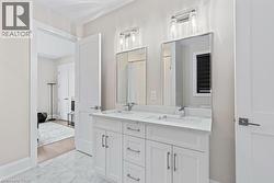 Full bathroom with double vanity, marble finish floor, baseboards, and a sink - 