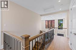 Hallway with an upstairs landing, recessed lighting, light wood finished floors, a tray ceiling, and baseboards - 