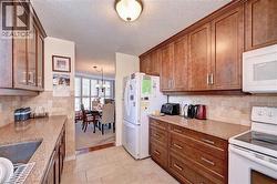 Kitchen with white appliances, a chandelier, brown cabinets, tasteful backsplash, and a textured ceiling - 
