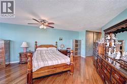 Bedroom featuring wood finished floors, a textured ceiling, baseboards, a closet, and ceiling fan - 