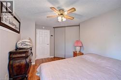 Bedroom with wood finished floors, a closet, a textured ceiling, and ceiling fan - 