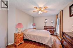 Bedroom featuring a textured ceiling, light wood finished floors, a ceiling fan, and baseboards - 