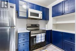Kitchen featuring blue cabinetry, appliances with stainless steel finishes, and light countertops - 