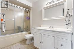 Full bath featuring vanity, shower / bath combination with glass door, and light tile patterned flooring - 