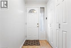 Doorway with wood finished floors and crown molding - 