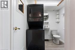 Bathroom featuring vanity, stacked washer and clothes dryer, a paneled ceiling, and light wood finished floors - 