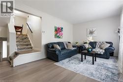 Living room featuring wood finished floors, stairs, and ornamental molding - 
