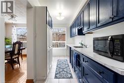 Kitchen with stainless steel microwave, blue cabinetry, and light tile patterned floors - 