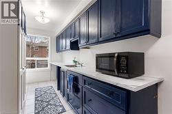 Kitchen featuring blue cabinetry, light tile patterned flooring, and light stone counters - 
