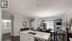 Kitchen with white cabinetry, a fireplace, open floor plan, dark wood-style flooring, and stainless steel dishwasher - 
