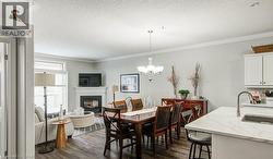 Dining area with ornamental molding, a glass covered fireplace, dark wood-style floors, a chandelier, and a textured ceiling - 