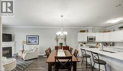 Dining room with a chandelier, crown molding, dark wood-type flooring, a glass covered fireplace, and a textured ceiling - 