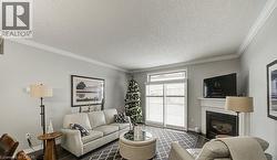 Living room with a textured ceiling, a fireplace, wood finished floors, and crown molding - 