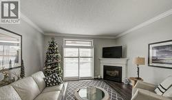 Living area featuring a textured ceiling, a glass covered fireplace, wood finished floors, and crown molding - 
