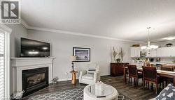 Living area with ornamental molding, a chandelier, dark wood finished floors, a glass covered fireplace, and a textured ceiling - 
