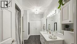 Full bath with dark marble finish flooring, vanity, a shower with curtain, and a chandelier - 