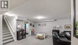 Living room featuring a textured ceiling, light carpet, and stairs - 