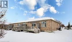 Snow covered house with brick siding and a wooden deck - 