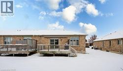 Snow covered house featuring brick siding and a deck - 