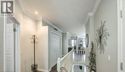 Hallway with an upstairs landing, ornamental molding, and dark wood-style flooring - 