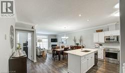 Kitchen with appliances with stainless steel finishes, open floor plan, white cabinets, light stone counters, and a textured ceiling - 