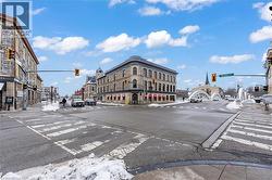 View of asphalt road featuring traffic lights, sidewalks, street lighting, and curbs - 
