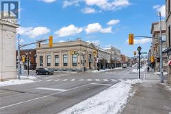 View of asphalt road with traffic lights, street lights, sidewalks, traffic signs, and curbs - 