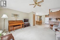 Living area with light carpet, ceiling fan, a textured ceiling, and vaulted ceiling - 